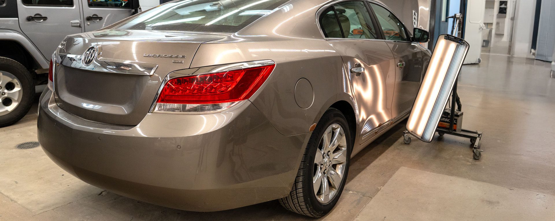 Car in Northland body shop with paintless dent removal light shining on it