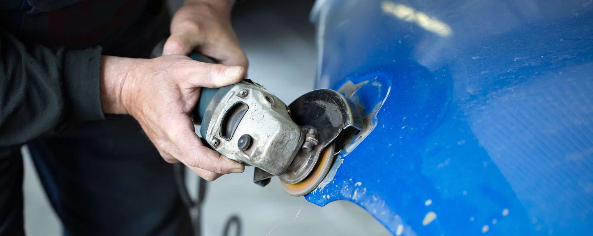 Man using a grinder on a car